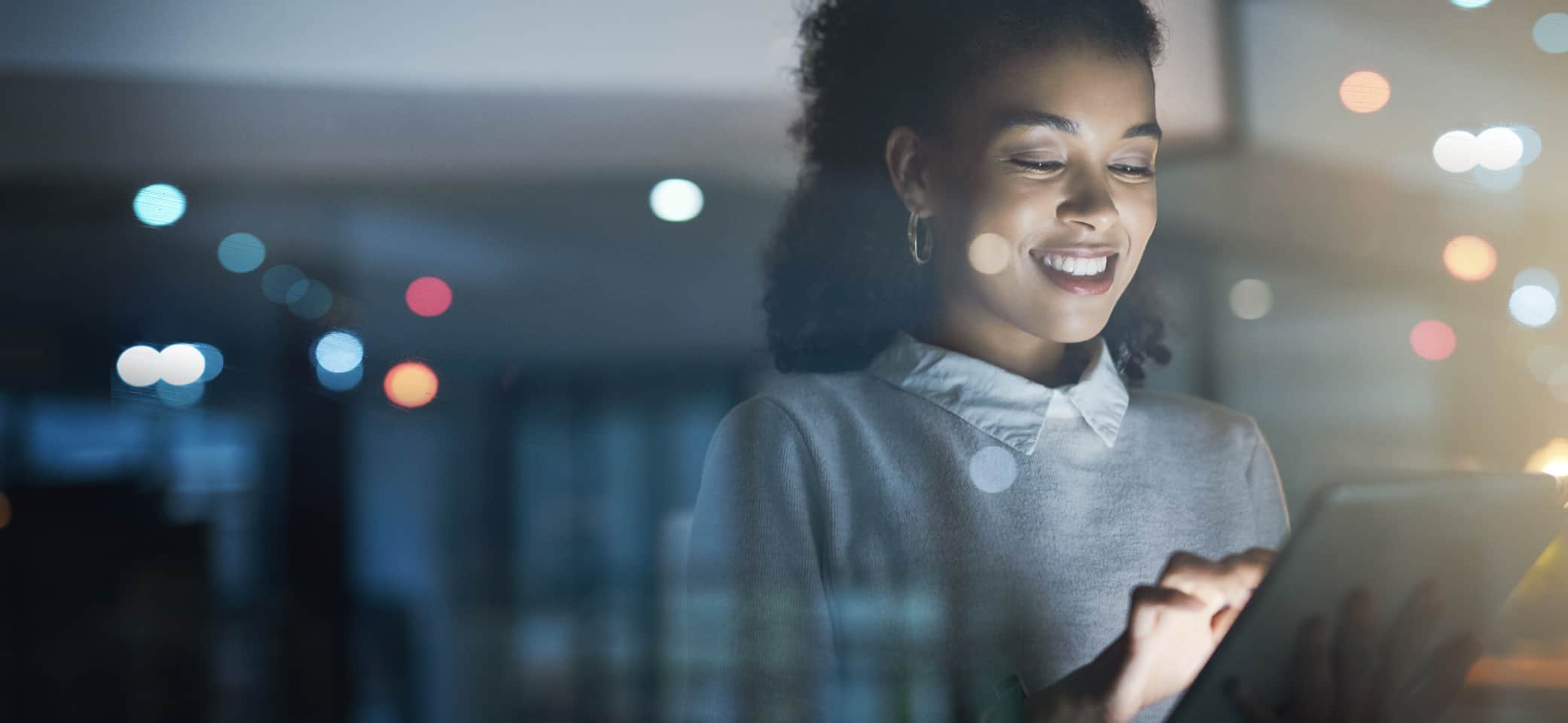 Woman smiling while using a tablet in a bright office