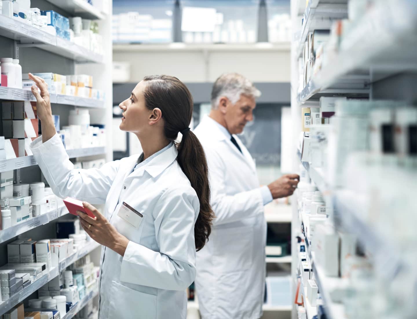 Pharmacists checking medication on shelves