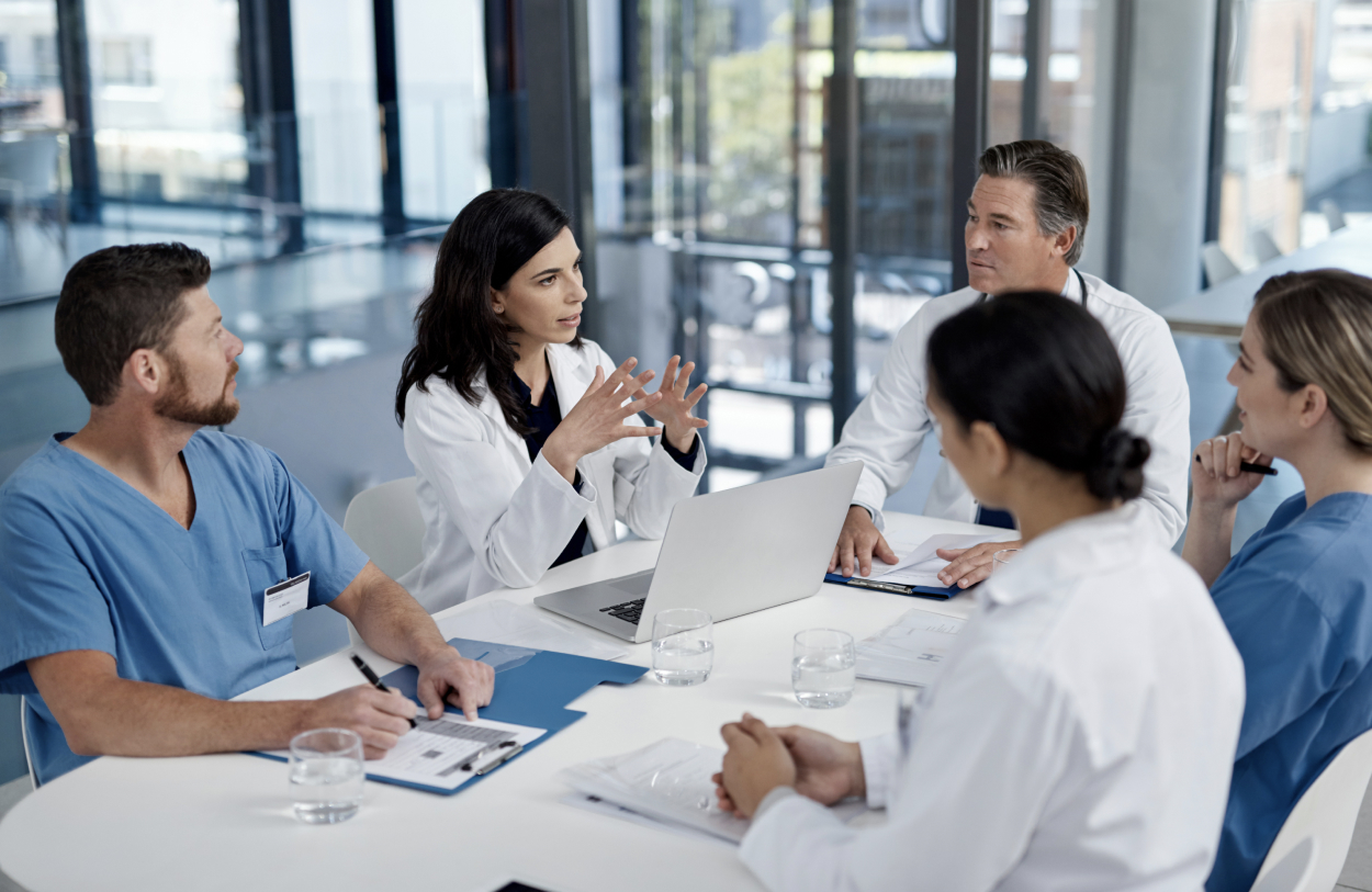Medical staff in scrubs discussing work at a laptop
