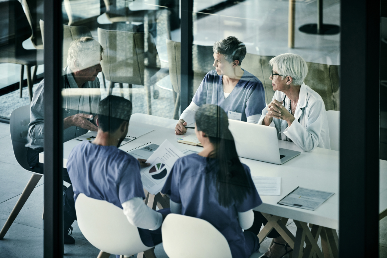 Colleagues working around a laptop, seen through glass
