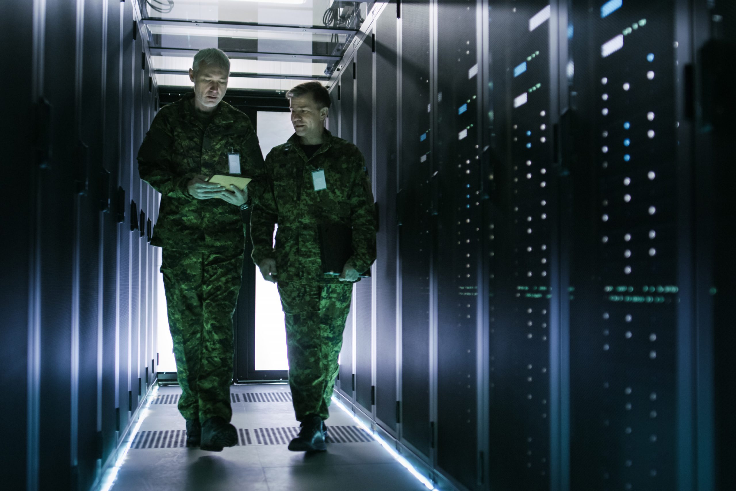 Two uniformed personnel walking through a server room
