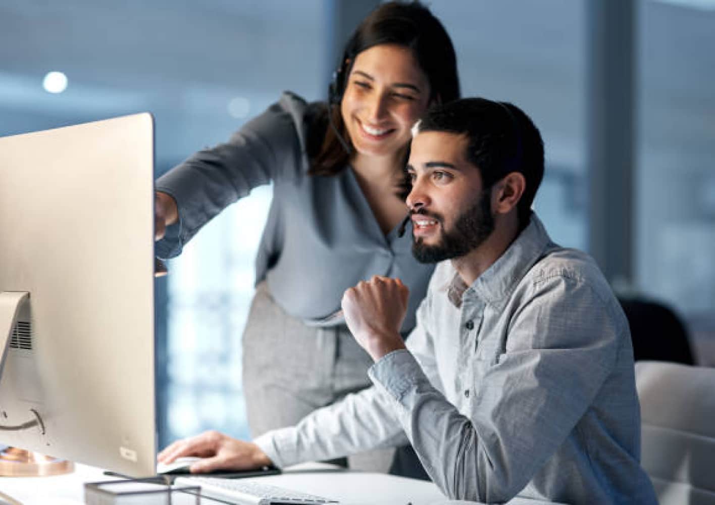 Two colleagues smiling at a computer screen