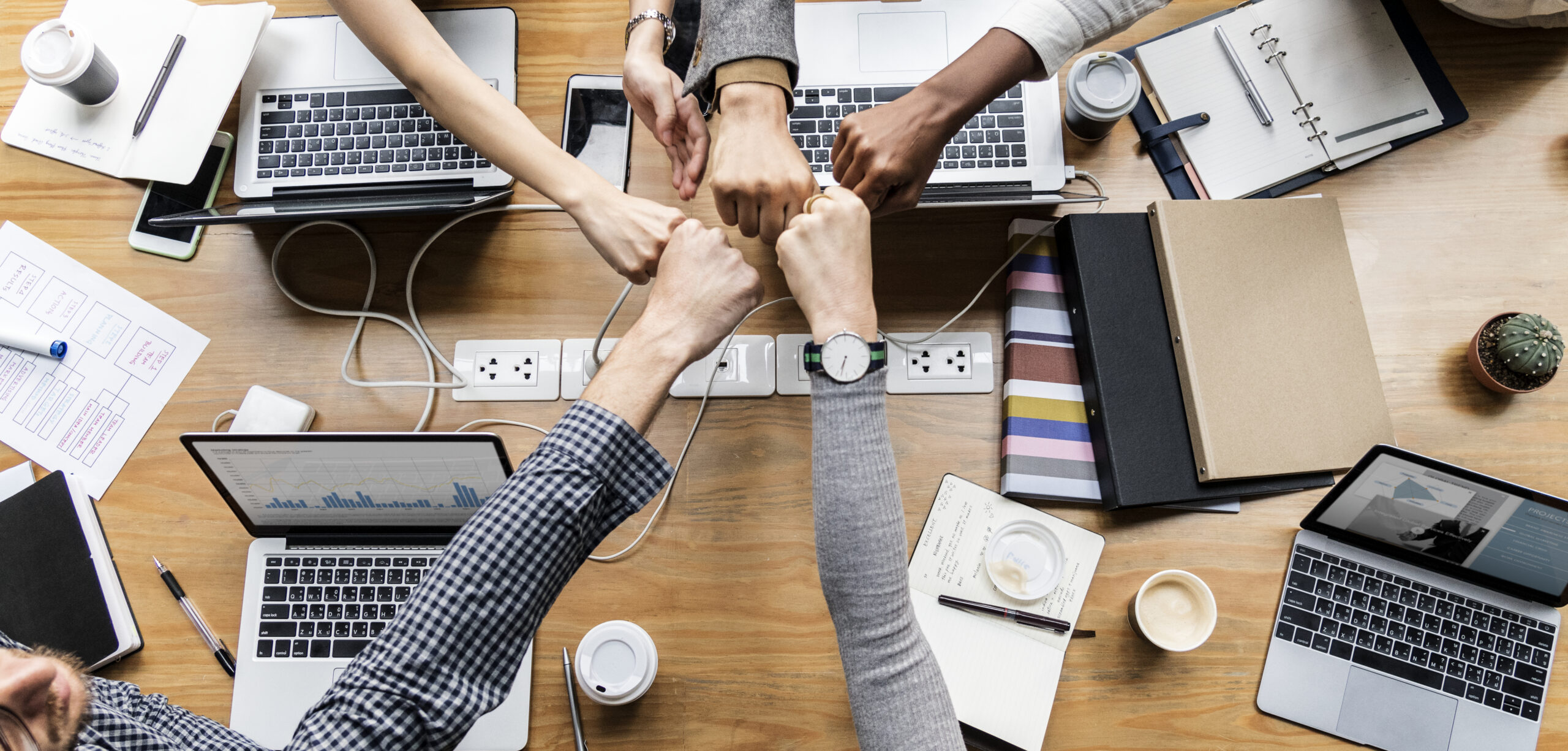 Colleagues fist-bumping over a table of laptops