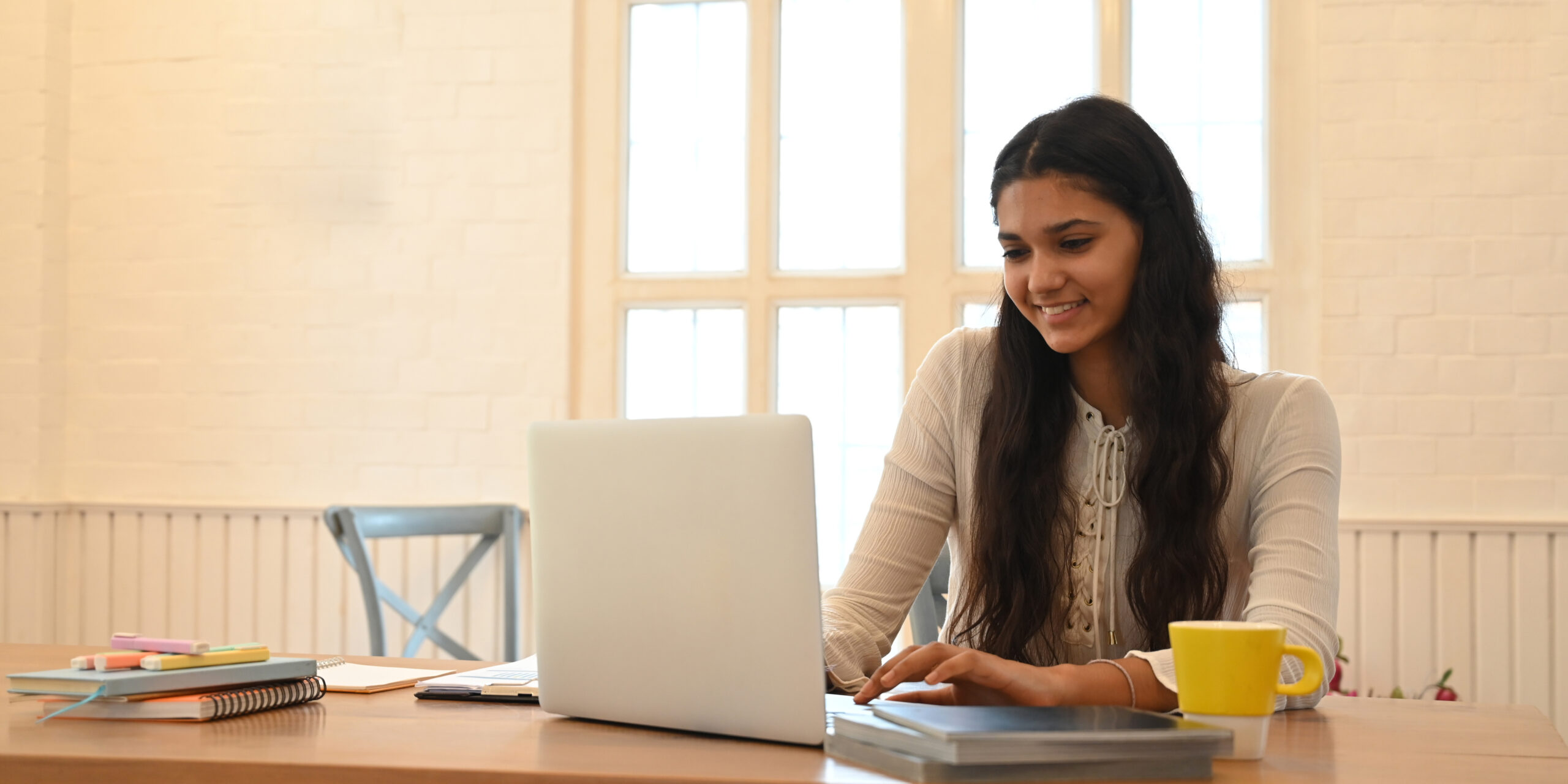 Student studying online at a laptop on a wooden desk
