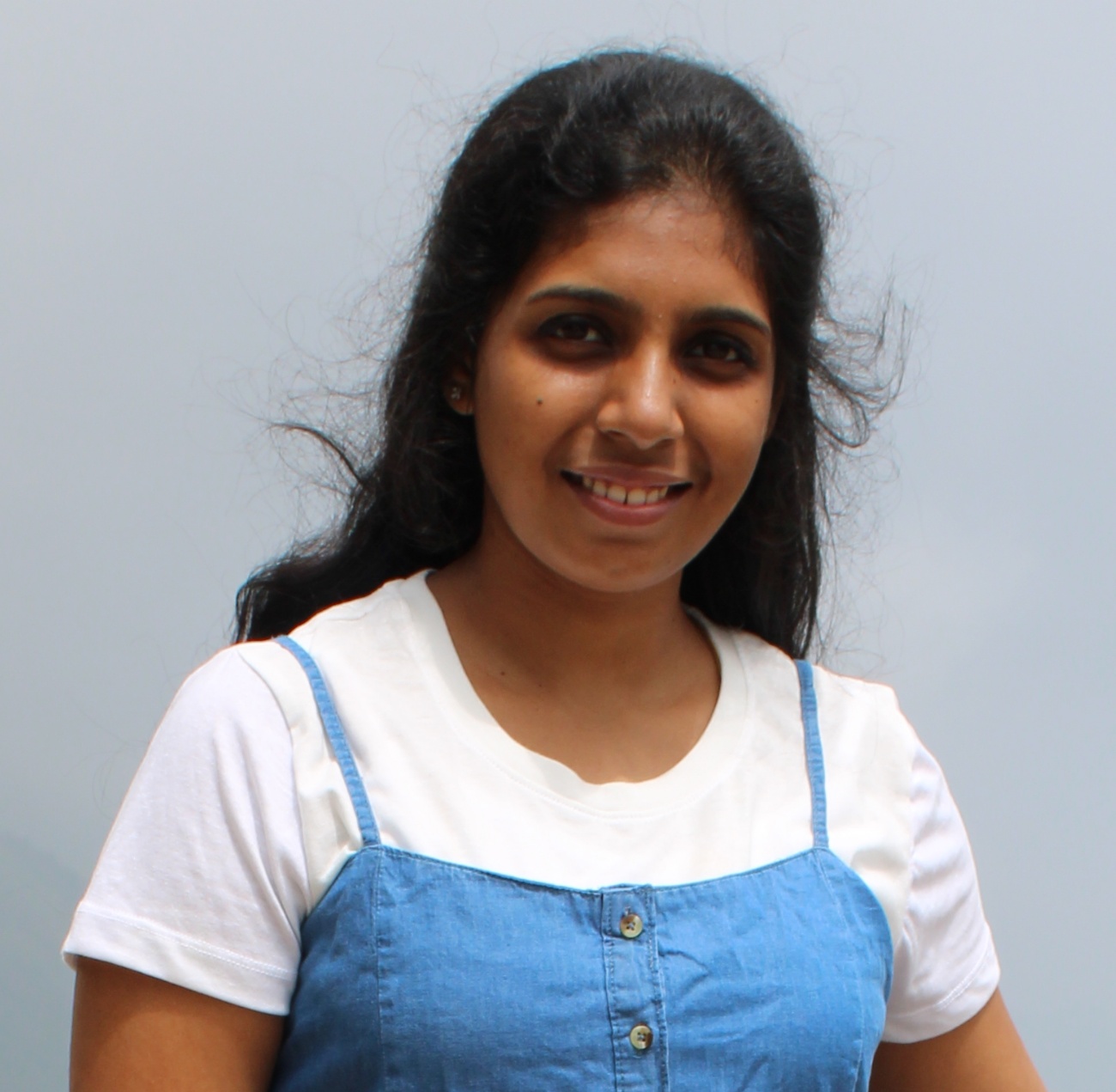 Portrait of a smiling woman in a white top and blue apron