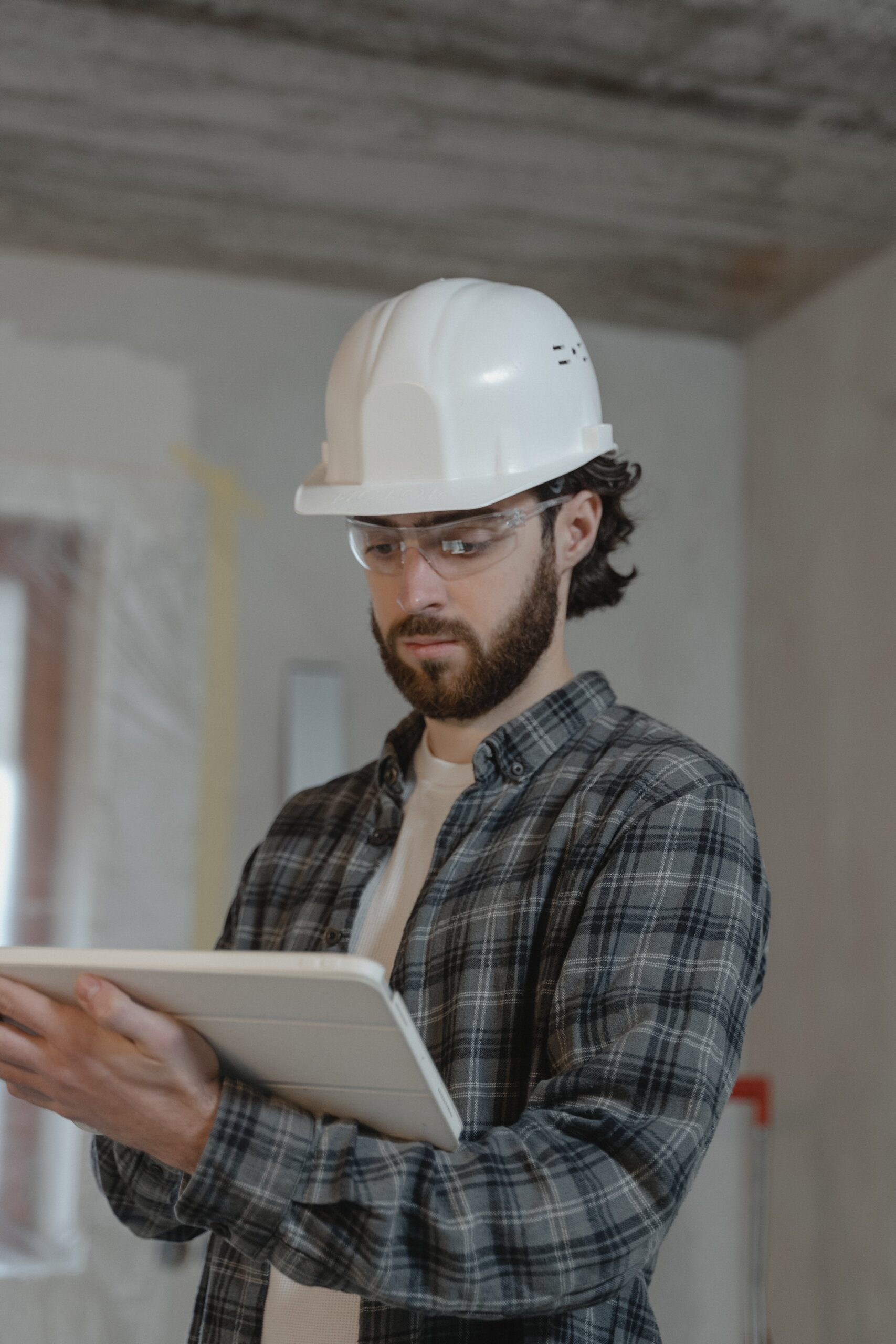 Engineer in a hard hat holding a tablet outdoors