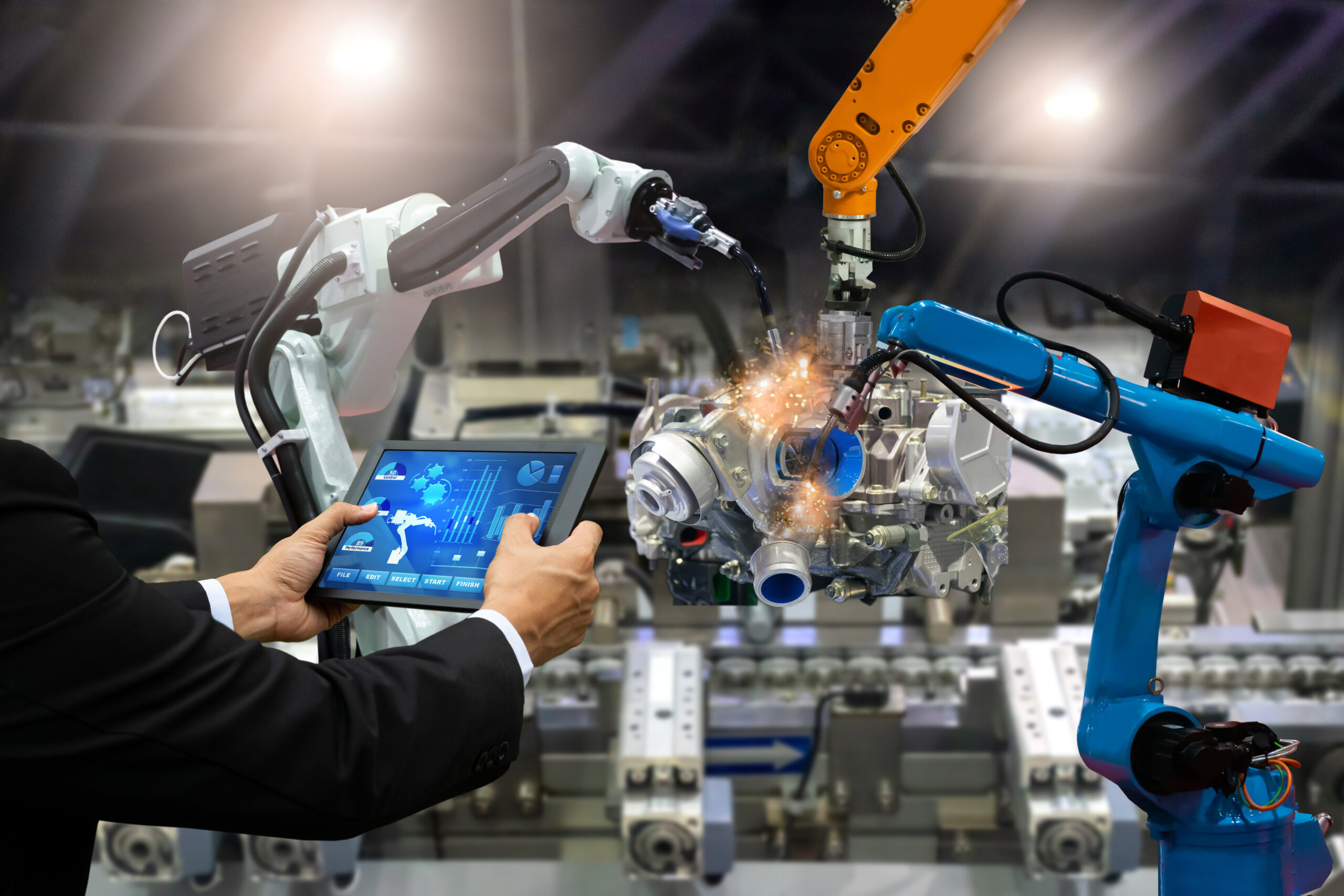 Engineer controlling robotic arms on a production line with a tablet